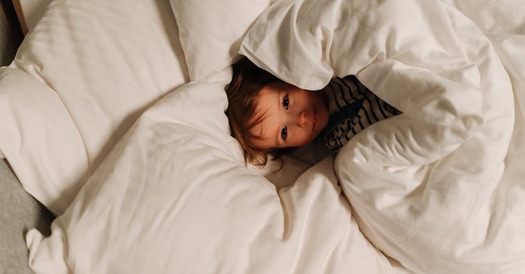 image of a little girl wrapped in a comforter on a bed