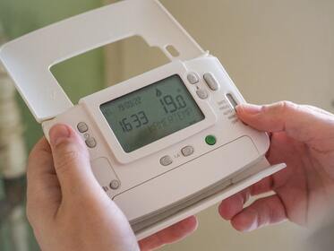 photo of someone holding a home HVAC thermostat
